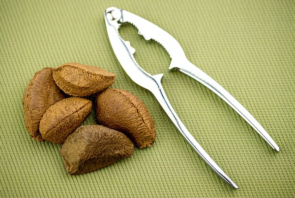 Brazil nuts with nut cracker on textured background — Stock Photo, Image