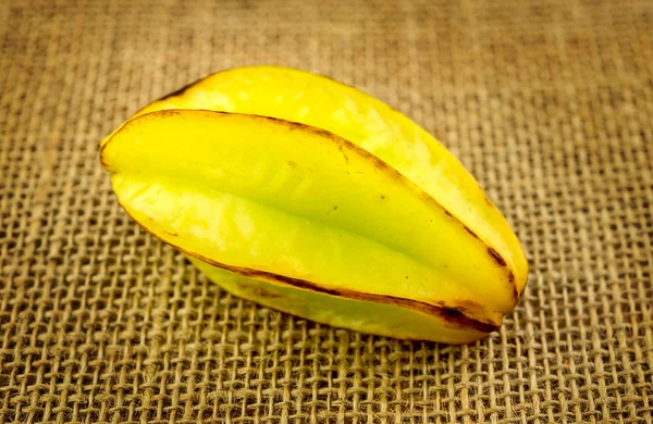 Carambola de una sola fruta estrellada contra fondo de arpillera hessian —  Fotos de Stock