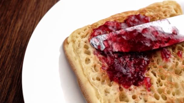 Slow motion closeup of delicious jam being spread on English crumpet — Stock Video