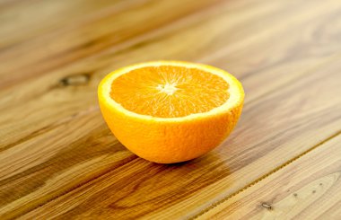 Juicy cut orange on wooden background clipart