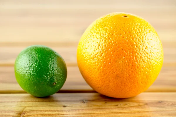 Яскравий апельсин і лайм на дерев'яному фоні — стокове фото