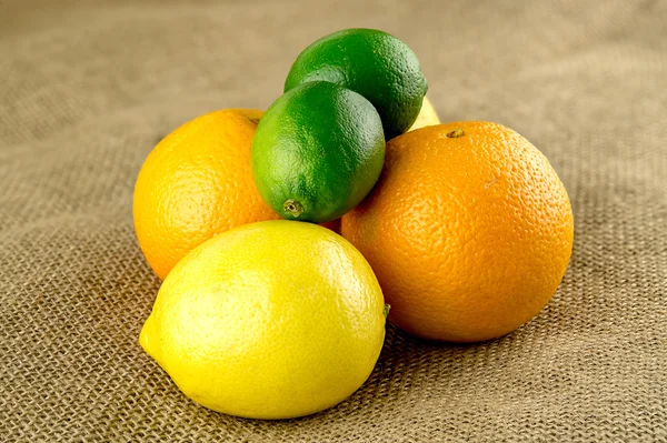 Limes, sinaasappelen en citroenen in stapel op boerderij verse Hessiaan tas — Stockfoto