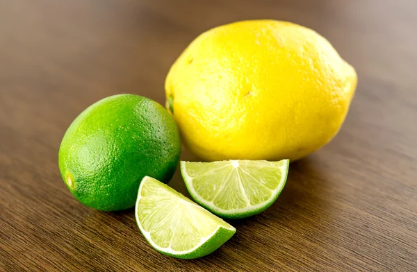 Wyciąć limonki i cytryny na drewniane tła — Zdjęcie stockowe