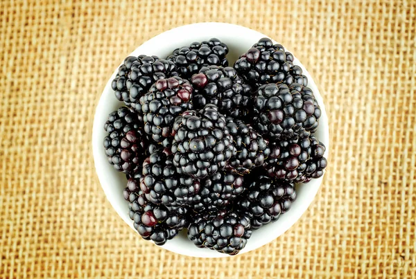 Macro of blackberries in white bowl against hessian background — Stock Photo, Image