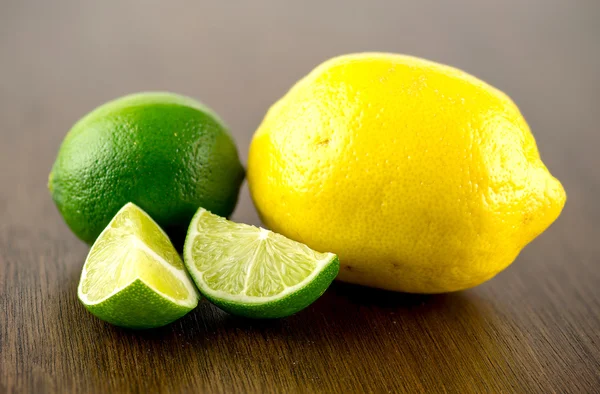 Delicious chopped limes and whole lemon on dark woody oak backgr — Stock Photo, Image