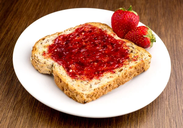 Strawberry jam spread on multi-grain toast — Stock Photo, Image