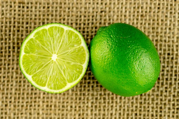 Levendig groen pittig verse limes, geheel en de helft gesneden kalk — Stockfoto