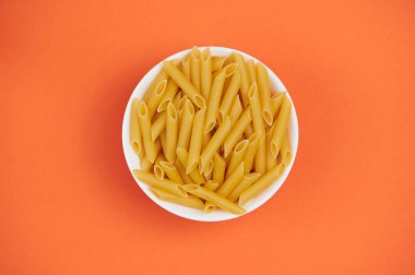 Turuncu arka planda erişteli bir kasenin üst görüntüsü.