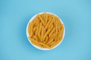 Mavi arka planda çiğ şehriye olan bir kaseye yaklaş.