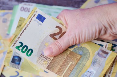 Kadın eli bir yığın Euro banknotunu tutuyor.