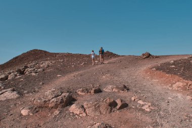 İspanya 'nın Lanzarote şehrinde kırmızı bir dağda yürüyüş yapan iki kişi.