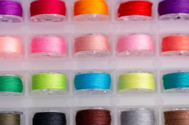 Renkli iplik makaraları bir depo kutusunda düzenlenir.