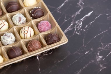 Çeşitli çikolatalı trüf mantarları siyah bir tezgahta bir tepside otururlar..