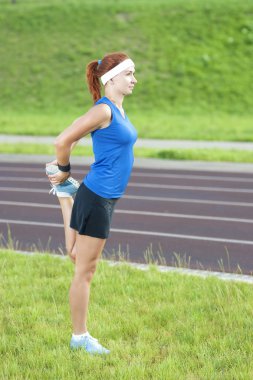 Young Red Haired Ginger Caucasian Female in Athletic Sportgear Having Legs Stretching  Excercises Outdoors
