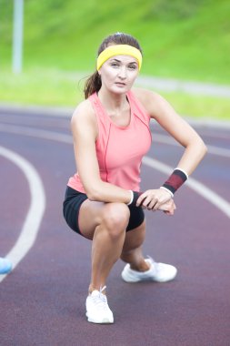 Young Caucasian Brunette Female in Athletic Sportgear Having Legs Stretching  Excercises Outdoors.
