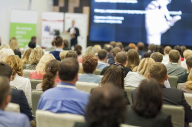 Seyirciler önünde iş toplantısında konuşan erkek ev sahibi