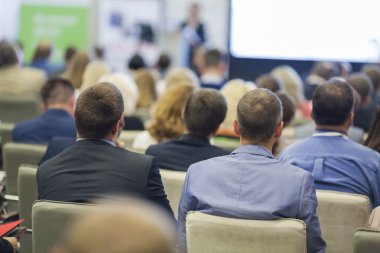 Büyük seyirci önünde iş toplantısında konuşan profesyonel kadın ev sahibi