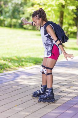 Tekerlekli paten üzerinde eğleniyor mutlu etkin ve sportif Afrikalı-Amerikalı kadın genç