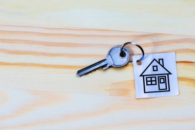 Tahta yüzeyde gümüş anahtarla birlikte ev sembolü. Yatay Resim