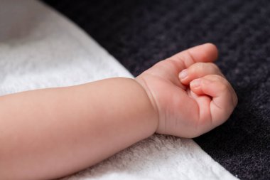 Dört haftalık erkek bebek kolunun yakın çekimi ve beyaz battaniyeye karşı minik parmaklar. Yatay Yönlendirme