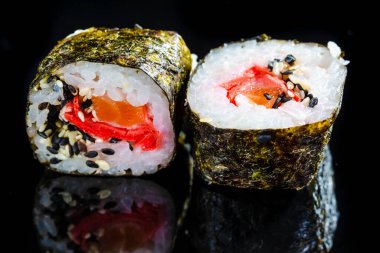 Japon Mutfak Fikirleri. Siyah Yansıtıcı Yüzeyde Somon, Zencefil ve Portakallı İki Geleneksel Suşi Yuvarlanışı. Yatay Görüntü