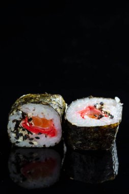 Mutfak fikirleri. Somon, Zencefil ve Portakallı İki Geleneksel Suşi Rolls On Black Reflective Surface. Dikey Görüntü