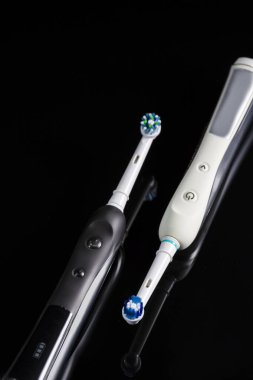 Oral Bakım Konsepti. Siyah Arkaplanda Profesyonel Elektrikli Diş Fırçası Çifti. Dikey Resim