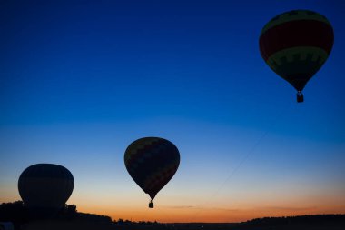 Alacakaranlıkta açık mavi gökyüzüne karşı havada yükselen üç renkli balon. Yatay Resim Kompozisyonu