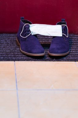 Koruyucu Sembol olarak Yüzü Tıbbi Maske ile kaplı Mens mavi süet yarı brogue botlar. Dikey Resim Kompozisyonu