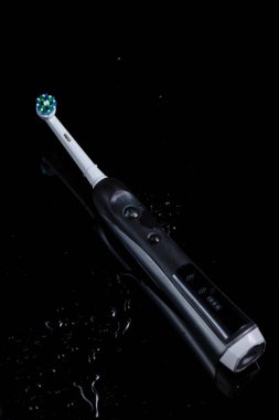 Oral Bakım Konsepti. Profesyonel Elektrikli Diş Fırçası ve Siyah Arkaplan Üzerine Su Sıçratma. Dikey Resim