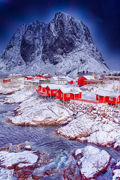 Norway Traveling. Famous Tourist Attraction Hamnoy Fishing Village at Lofoten Islands in  Norway With Red Rorbu Houses and Falling Snow. Vertical Image