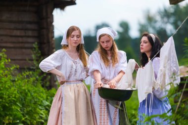 Kırsal alanda Çarşaf Havzası 'nda Geleneksel Kırsal Kostümlerle Birlikte Duran Üç Güzel Beyaz Kız Arkadaş Grubu. Yatay Çekim