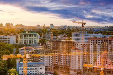Mimarlık Konseptleri. Bulutlu güneşli gökyüzüne karşı vinçler inşa edilen inşaat sahasının üst görüntüsü. Yatay Resim