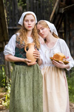 Kırsal Tarz Kavramları. Caly Jar ve Birlikte Ekmek Yiyen Geleneksel Kırsal Kıyafet Pozisyonunda İki Genç Güzel Beyaz Kız Arkadaş. Dikey Resim Kompozisyonu