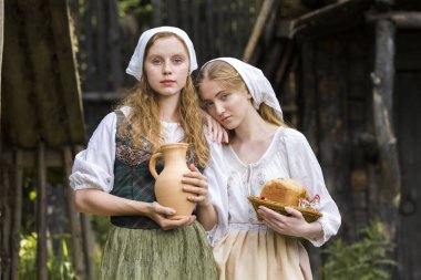 Kırsal Tarz Kavramları. Caly Jar ve Birlikte Ekmek Yiyen Geleneksel Kırsal Kıyafet Pozisyonunda İki Genç Güzel Beyaz Kız Arkadaş. Yatay Resim Yönlendirmesi