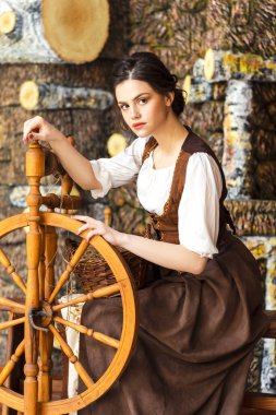 Genç, güzel, beyaz, esmer kadın. Köy ortamında Retro Elbiseli Dönen Tekerlekli Kadın pozu. Dikey Çekim