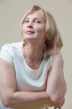 Olgun Kafkas Sarışın Kadın bej arka planda Kaldırılmış Elle Günlük Giysiler Giyiyor. Dikey resim