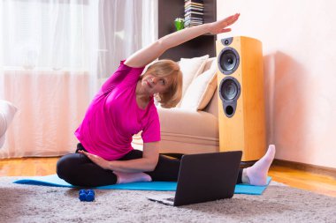 Spor Konseptleri. Evde Uzaktan İnternet Oturumu sırasında Mavi Mat 'te Yoga Yapan Olgun Kafkas Kadınları. Yatay Resim Kompozisyonu