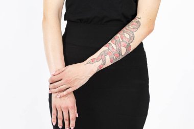 Beyaz üzerine siyah elbise giymiş, elinde yılan dövmesi olan beyaz bir kadın vardı. Yatay Resim