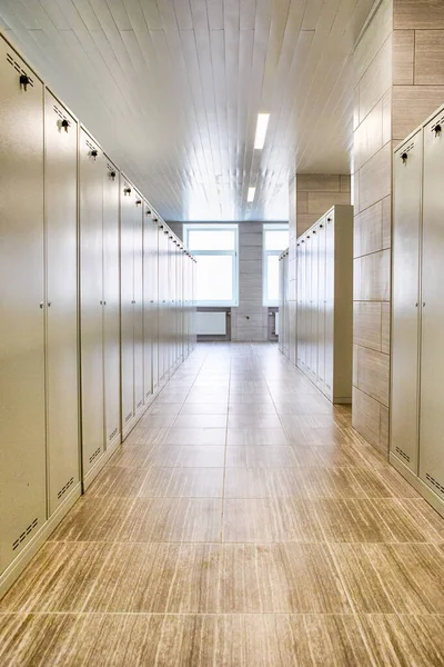 Architecture Concepts. Indoors View of Long Industrial Tile Corridor With Metal Lockers. Vertical Image Orientation