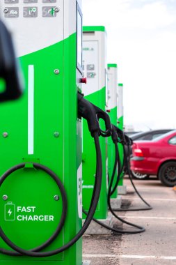 Alternatif Enerji Konsepti. İstasyonda elektrik kablosu takılı elektrikli araba ya da EV araba şarjı. Dikey Resim