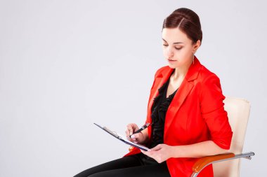 İş dünyasındaki kadınlar. Resmi Giysili Esmer Kadın Kağıt Klasörle Sandalyede Otururken Not Tutuyor. Yatay Resim Kompozisyonu