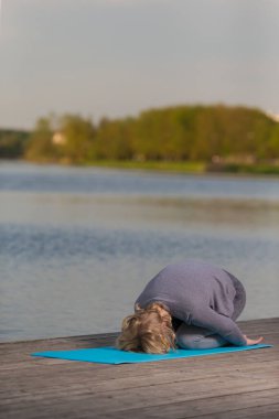Yoga Bükme Eğitimi sırasında Su Yakınındaki Ahşap Sahne 'de Profesyonel Spor Kıyafeti Giyen Kıdemli Beyaz Kadın. Dikey Resim