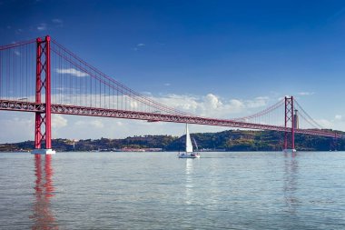 Portekiz Seyahat Fikirleri. Portekiz 'deki Lizbon' da 25 Nisan Köprüsü 'nde Tagus Nehri' nde turist grubuyla bir yelkenli tekne. Yatay Görüntü