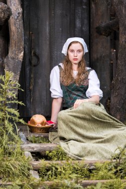 Beyaz, genç, beyaz, kızıl, kadın pozu. Village Outdoor 'da ev yapımı ekmek sepeti var. Dikey Resim Kompozisyonu