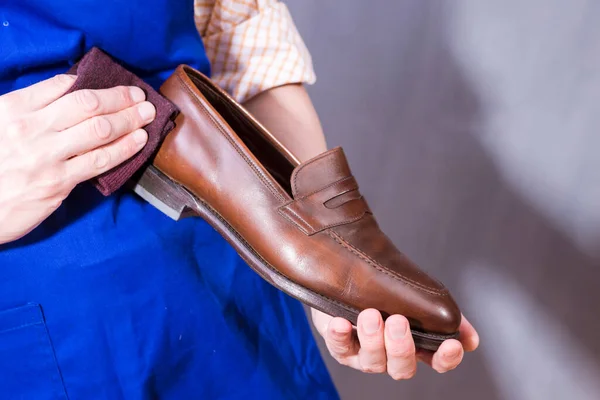Male Shoes Cleaner with Cloth For Brown Leather Penny Loafers Shoes While Cleaning in Workshop. Horizontal Composition