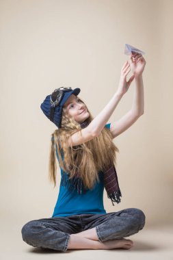 Uçan Gear 'lı Kafkas Sarışın Kız Bej Arkaplan Üzerinde Origami Kağıt Uçağı Fırlatıyor. Dikey Resim