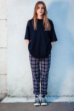 Beyaz Duvara Karşı Siyah Gömlekli Sarışın Kız 'ın Tam Uzun Portresi. Dikey Resim Kompozisyonu