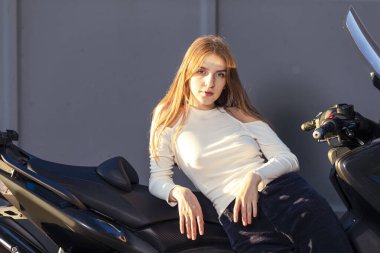 Moto fikirleri. Yaşam stili fikirleri. Genç Şehvetli Beyaz Kadın Bisikletçi Açık Hava Spor Bisikletine yaslanıyor. Yatay Resim Kompozisyonu