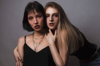 İki Kafkas Kız Arkadaşı Gri Arkaplan Üzerine Kucaklaşıyor. Yatay Resim Bileşimi